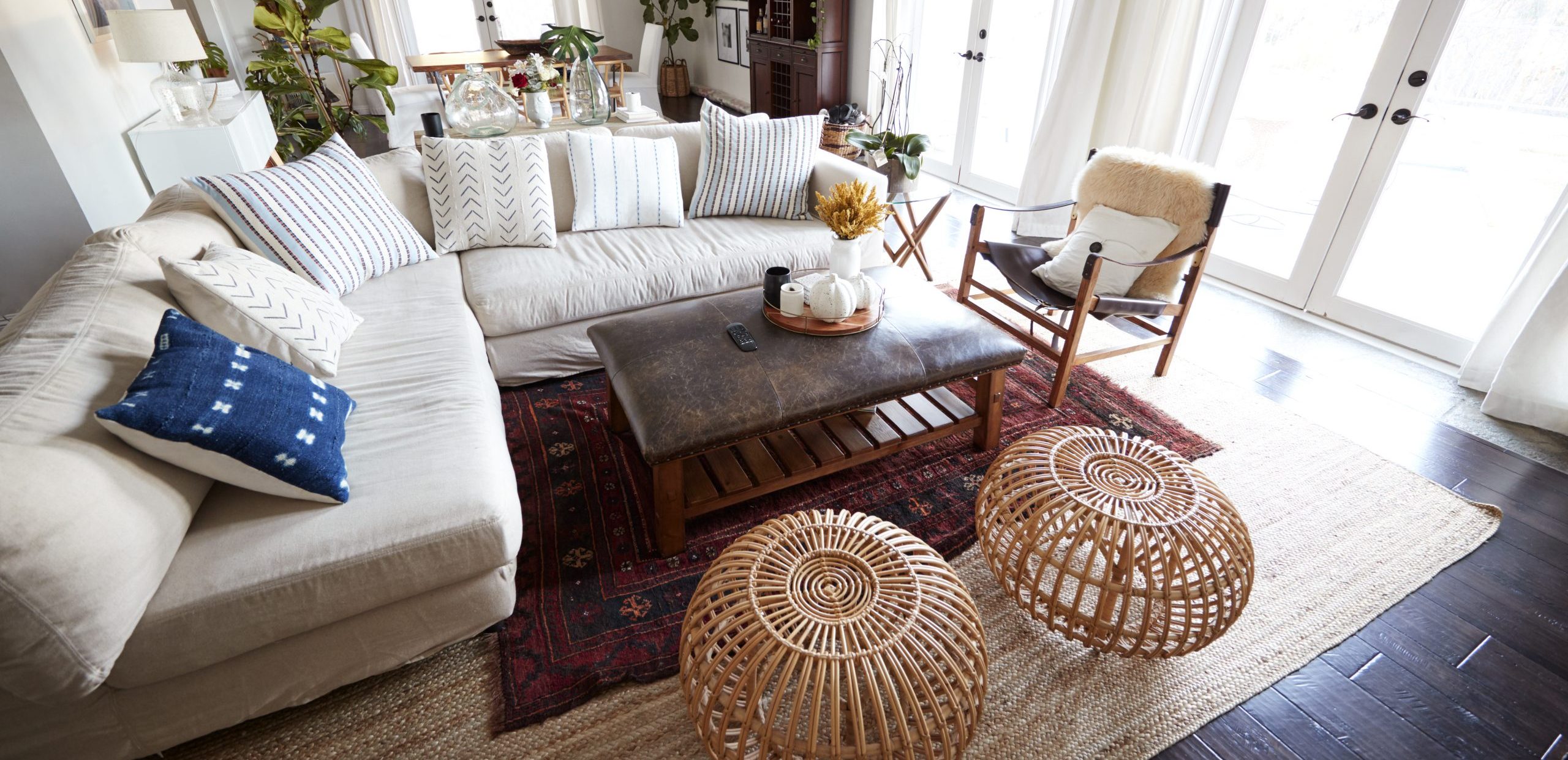 A family living room with French windows and a large comfortable corner sofa, seen in daylight, incidental people in shot