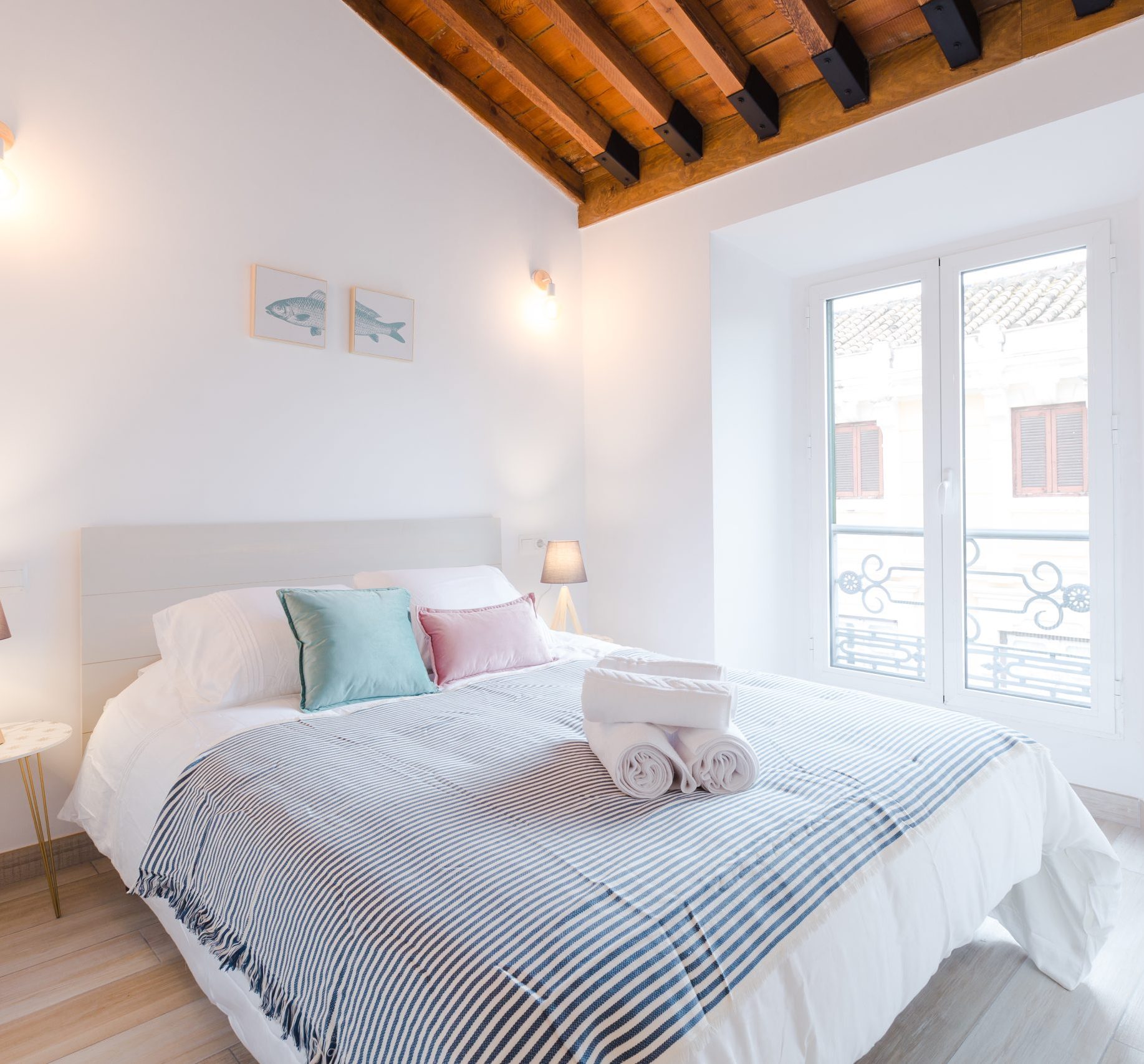 Comfortable light room with big bed and lamps near window in modern house